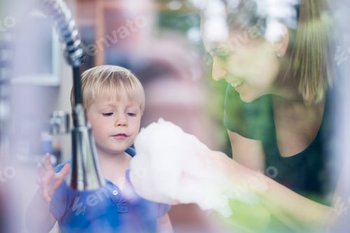 Preview: Young boy fascinated by soap bubbles with smiling woman in the background