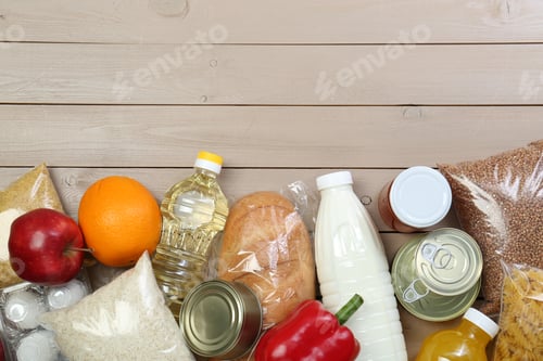 Preview: Different donation food on wooden table, flat lay. Space for text