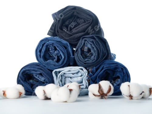 Preview: Stack of rolled jeans and cotton flowers on light background