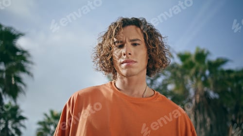 Preview: Portrait confident curly guy looking camera. Trendy young hipster posing outdoor