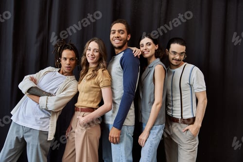 Preview: cheerful multiethnic startup team posing near black drape in modern office, unity in business