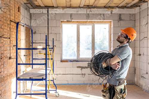 Preview: Electrician contractor with electric cable at a construction site.