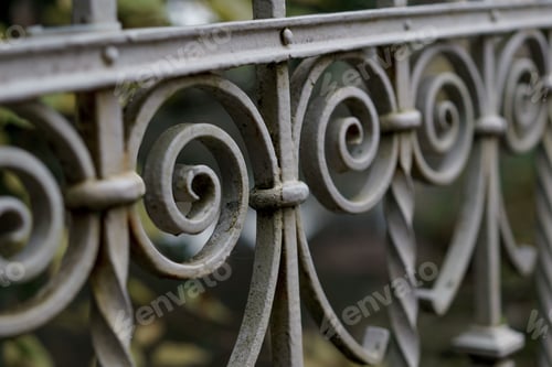 Preview: Close-up shot of a metal wrought fence set in a natural park setting with greenery in the background