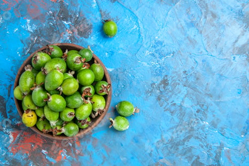 Preview: Overhead view of delicious vitamin bomb fresh feijoas in a brown pot on blue background