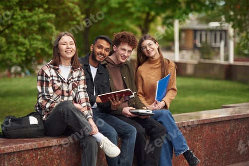 Preview: Smiling Students Relaxing with Books Outdoors at School