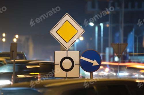 Preview: Roundabout road signs with blurred cars on city street traffic at night.