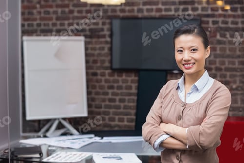 Preview: Asian midadult female standing, wearing cardigan, smiling in office near monitor, copy space