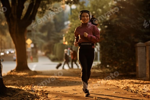 Preview: Full length of Asian sportswoman jogging on the street.