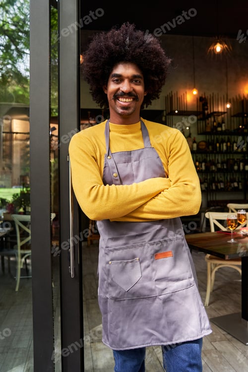 Preview: Young entrepreneur standing front of the camera and crossing arms smiling.