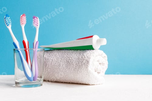 Preview: Healthy teeth. Toothbrush in a glass and toothpaste and bath towel on a table in the bathroom on a