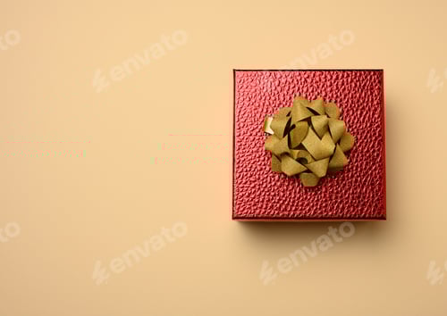 Preview: Red cardboard box tied with a silk red ribbon on a beige background
