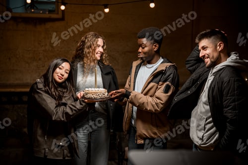 Preview: Friends celebrating with a cake in a cozy indoor setting during a night gathering