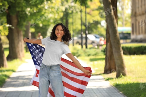 Preview: Happy young woman with American flag on sunny day