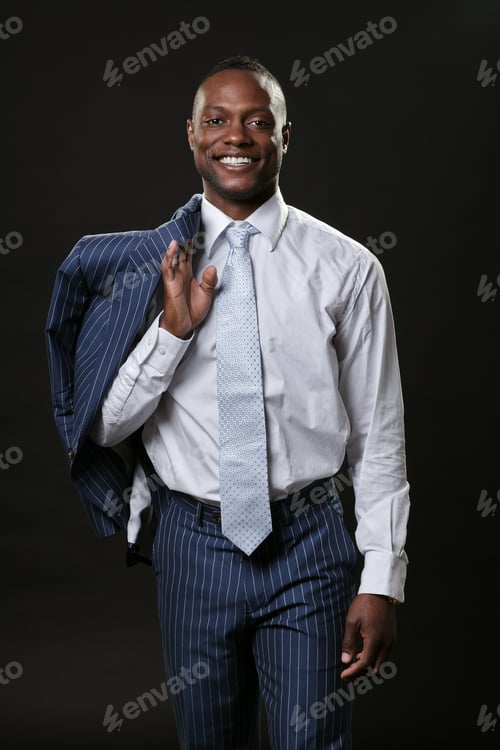 Preview: Young Black Business Man Smiling Wearing Blue Striped Suit Holds Jacket Over Shoulder.