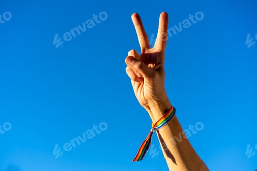 Preview: Hand of a woman with closed fist in favor of feminism, blue sky background