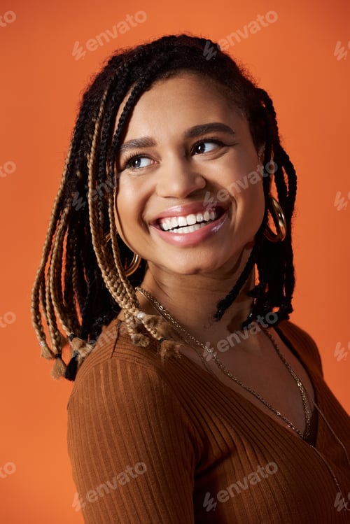 Preview: Young Black woman with braids poses against a colorful studio backdrop