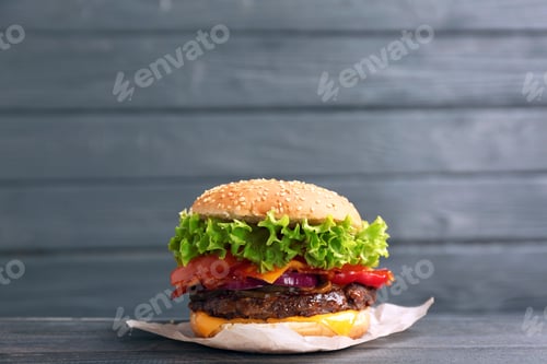 Preview: Tasty burger with bacon on table against wooden background