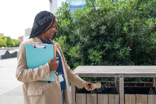 Preview: Woman recycling coffee cup in city trash can
