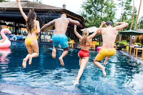 Preview: rear view of young friends having fun and jumping into swimming pool