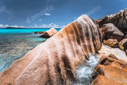 Preview: Bizarre formed rocks on Anse Cocos beach, La Digue island, Seychelles. Blue ocean bay in background