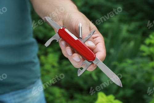Preview: Man holding compact portable multitool outdoors, closeup