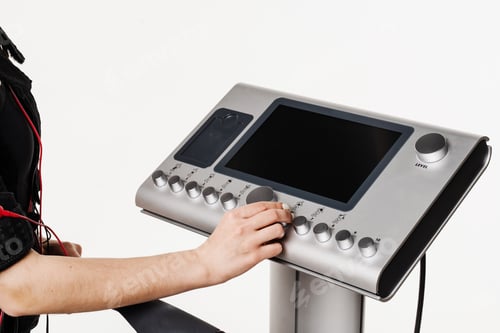 Preview: Female trainer adjusting EMS device before workout, close-up fitness technology