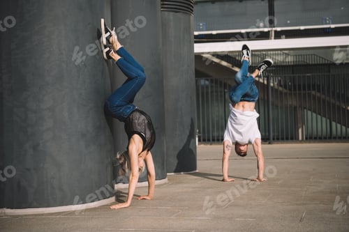 Preview: young couple of dancers performing handstand on street