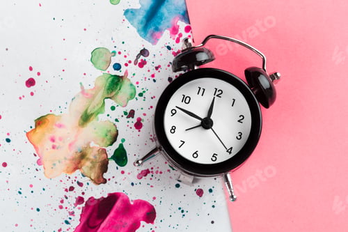 Preview: Vintage alarm clock on a creative colorful background with paint sprinkles