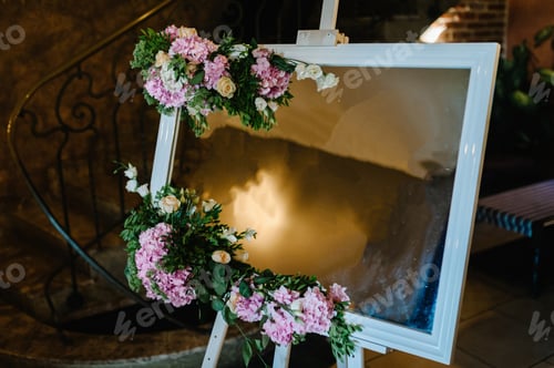 Preview: Wedding board mockup. Wedding white easel decorated with flowers, indoors.