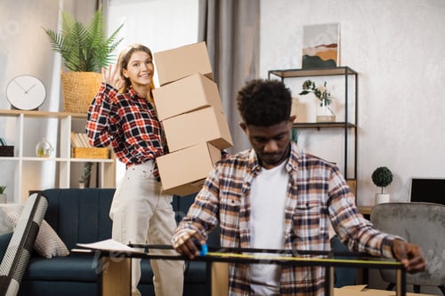 Preview: Woman holding boxes while man measuring shelves at new home