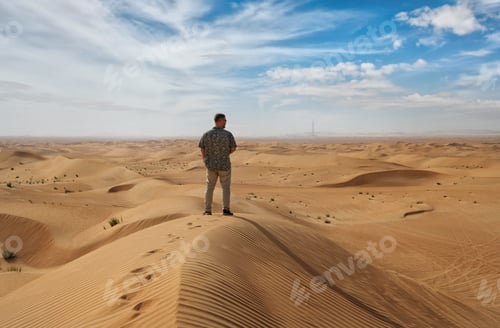 Preview: A man in light-colored clothes stands on a sand dune.