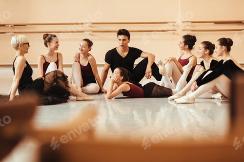 Preview: Group of ballet dancers and their instructor sitting on the floor and talking.