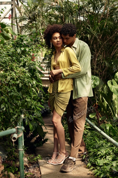 Preview: Young couple shares a tender moment among lush greenery in a vibrant greenhouse setting