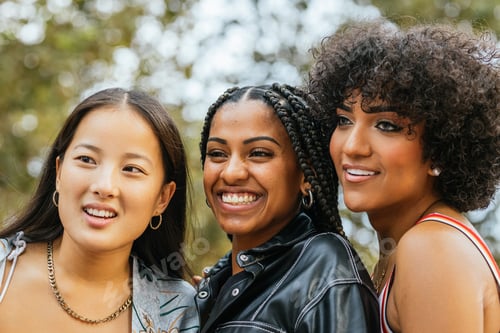 Preview: Vibrant young women of different ethnicities posing closely together outdoors.