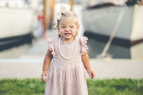 Preview: Funny baby girl in a cute pink dress, with a bow on the head