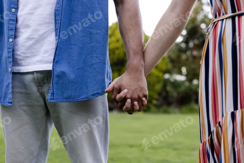 Preview: Young couple holding hands outdoors, enjoying peaceful moment together in park
