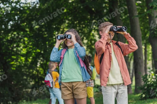 Preview: selective focus of cheerful kids looking through binoculars in park