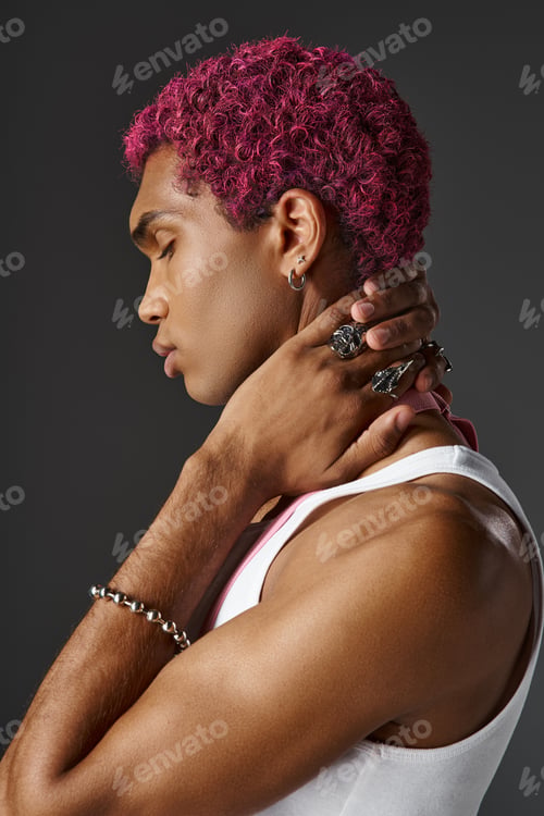 Preview: portrait of young man with pink suspenders posing in profile on gray backdrop, fashion and style