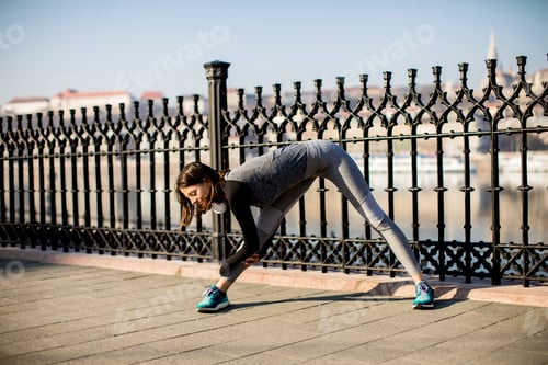 Preview: Young woman practices stretching after jogging outdoor