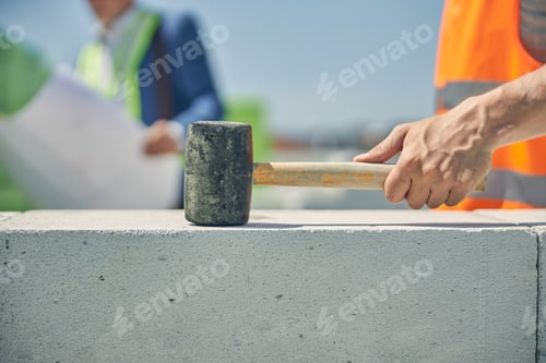 Preview: Male worker hand clutching a brick hammer