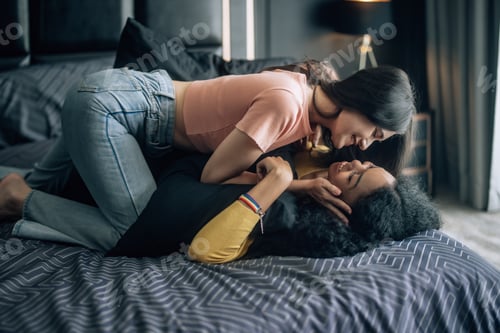 Preview: Lesbian partners share joy, play on bed, embrace, exchange tender kiss, radiating genuine happiness