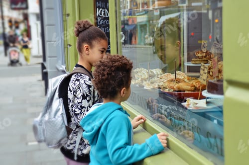 Preview: Kids looking at food through a shop window of a bakery