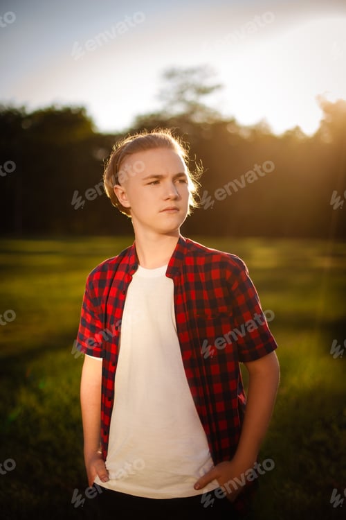 Preview: teenager boy dressed red casual shirt walking sunny park, school garden look into the distance
