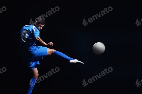 Preview: Soccer Player Doing Kick With Ball On Football Stadium Field Isolated On Black Background