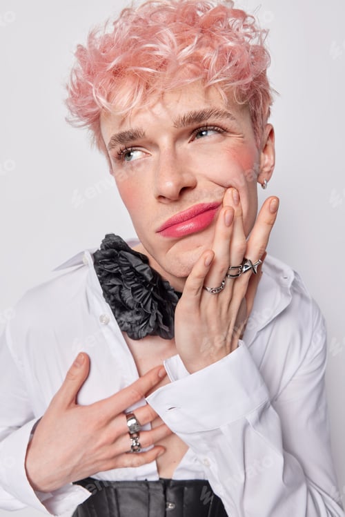 Preview: Vertical shot of thoughtful pink haired transgender man with makeup purses lips and looks displeased