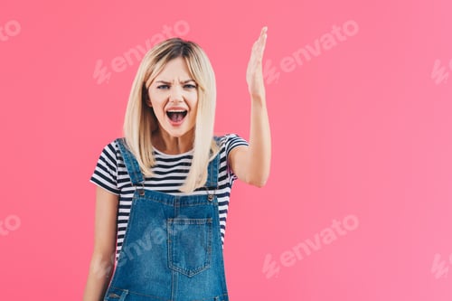 Preview: angry girl in denim overall yelling and gesturing isolated on pink