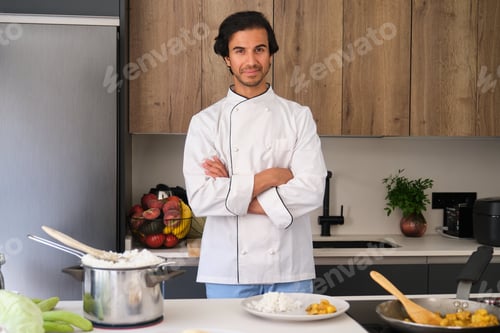 Preview: Indian chef smiling with arms crossed in a modern kitchen