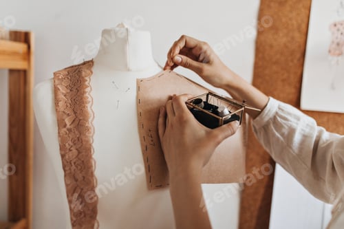Preview: Woman creates clothing patterns for mannequin. Girl in beige blouse working as fashion designer in