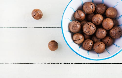 Preview: Organic Macadamia nuts (Macadamia integrifolia) in shell on wooden white table.