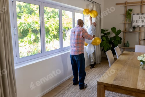 Preview: Senior friends decorating room with balloons for retirement celebration at home